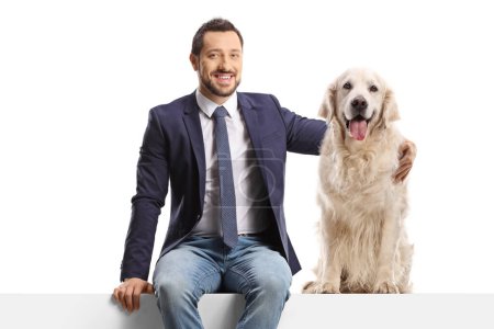Photo for Man sitting on a blank panel and hugging a retriever dog isolated on white background - Royalty Free Image