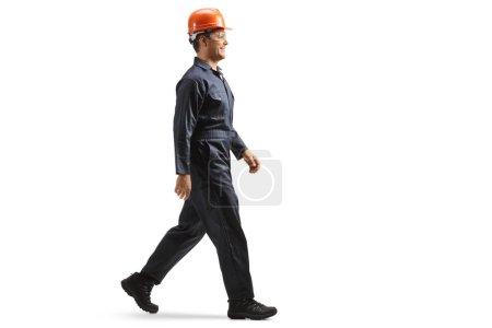 Foto de Foto de perfil completo de un trabajador de la fábrica que lleva casco y uniforme y camina aislado sobre fondo blanco - Imagen libre de derechos