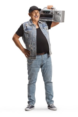Foto de Cheerful mature man standing and holding a boombox radio on his shoulder isolated on white background - Imagen libre de derechos