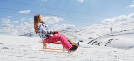 Téléchargez les photos : Girl on a snowy mountain riding a wooden sleigh - en image libre de droit