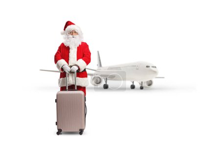 Foto de Full length portrait of santa claus standing with a suitcase in front of a plane isolated on white background - Imagen libre de derechos