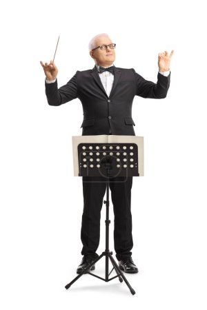 Photo for Full length portrait of a music conductor standing in front of a sheet music stand and directing a performance isolated on white background - Royalty Free Image