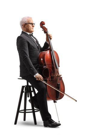Foto de Profile shot of a musician sitting on a chair with a cello music instrument isolated on white background - Imagen libre de derechos