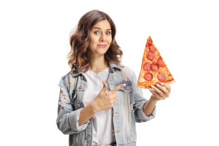 Photo for Young woman holding a yummy pepperoni pizza slice and pointing isolated on white background - Royalty Free Image