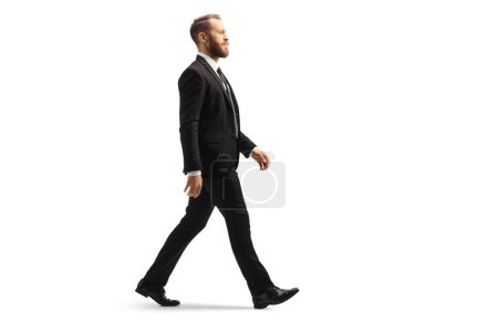 Téléchargez les photos : Professional man in a black suit walking isolated on white background - en image libre de droit