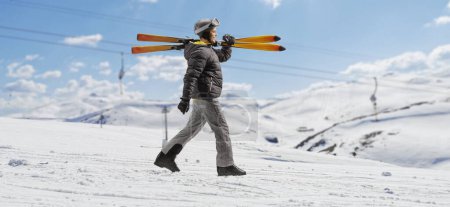 Foto de Full length profile shot of a man carrying skis on a mountain - Imagen libre de derechos