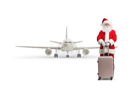 Photo for Full length portrait of santa claus standing with a suitcase in front of an airplane isolated on white background - Royalty Free Image