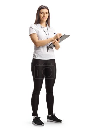 Photo for Full length portrait of a female sport coach holding a clipboard and smiling at camera isolated on white backgroun - Royalty Free Image