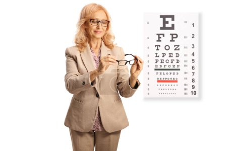 Photo for Mature woman trying glasses in front of an eyesight test isolated on white background - Royalty Free Image
