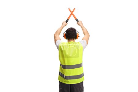Foto de Rear view shot of an marshaller signalling with crossed wands isolated on white background - Imagen libre de derechos