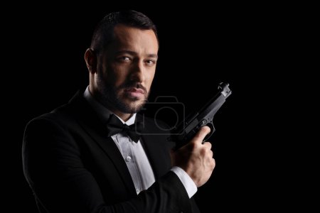 Foto de Secret agent holding a gun isolated over black background - Imagen libre de derechos