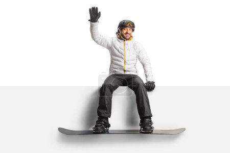 Photo for Man with a snowboard sitting on a blank panel and waving isolated on white background - Royalty Free Image