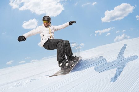Photo for Man riding a snowboard downhill on a snowy hill - Royalty Free Image