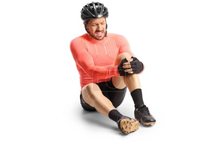 Foto de Injured bicycle rider sitting on the ground and holding his painful knee isolated on white backgroundd - Imagen libre de derechos