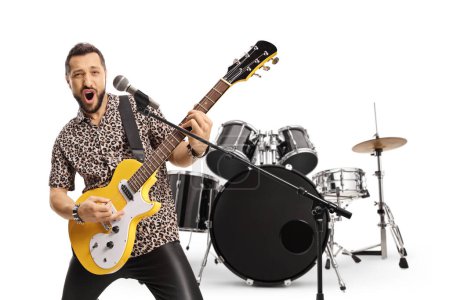 Photo for Male guitarist playing an electric guitar in front of drums isolated on white background - Royalty Free Image