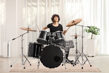 Téléchargez les photos : Young man playing drums at home inside a living room - en image libre de droit