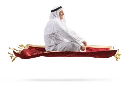Photo for Profile shot of an arab man flying on a carpet isolated on white background - Royalty Free Image