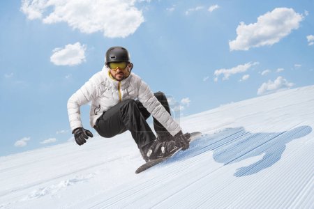 Photo for Man gliding with a snowboard downhill on a sunny day - Royalty Free Image