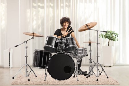 Photo for Young male drummer holding drumsticks and smiling inside a room - Royalty Free Image