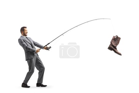 Foto de Full length profile shot of a businessman with an old boot on a fishing rod isolated on white background - Imagen libre de derechos