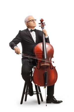 Photo for Full length portrait of a musician in a black suit and bow-tie sitting on a chair and playing a cello isolated on white background - Royalty Free Image