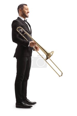 Photo for Full length profile shot of trombone player standing and smiling isolated on white background - Royalty Free Image