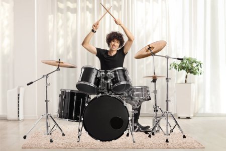 Foto de Young male drummer holding drumsticks up at home - Imagen libre de derechos