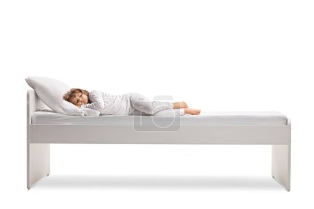 Téléchargez les photos : Little girl in pajamas sleeping in a comfortable bed isolated on white background - en image libre de droit