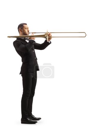 Photo for Full length profile shot of an elegant male musician playing a trombone isolated on white background - Royalty Free Image