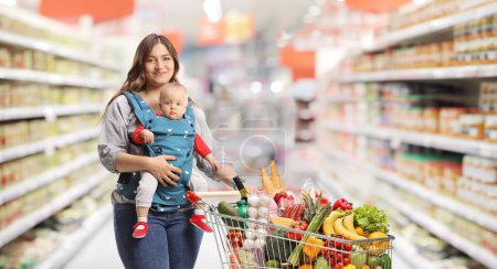 Téléchargez les photos : Mother with a baby shopping inside a supermarket - en image libre de droit