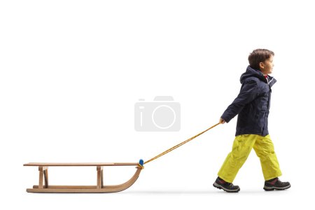 Téléchargez les photos : Full length profile shot of a boy pulling a wooden sleigh isolated on white background - en image libre de droit
