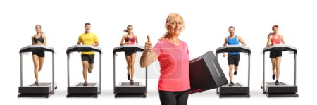 Photo for Woman holding a step aerobic platform and gesturing thumbs up and people running on treadmills isolated on white background - Royalty Free Image