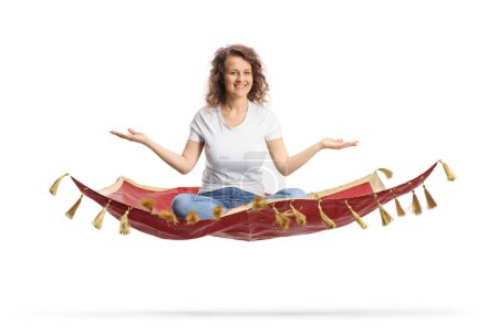 Photo for Young woman sitting on a flying carpet and gesturing with hands isolated on white background - Royalty Free Image