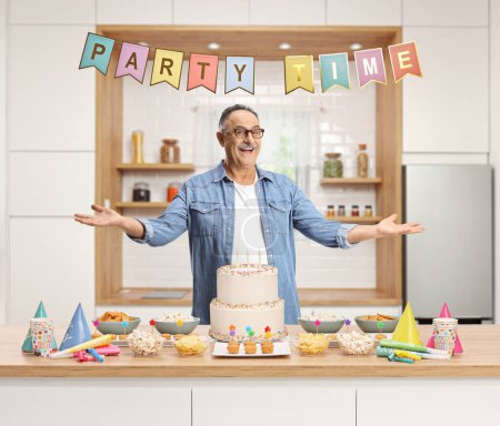 Téléchargez les photos : Mature man with a cake standing inside a kitchen and celebrating birthday - en image libre de droit