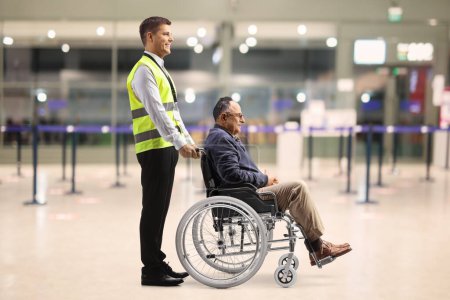 Téléchargez les photos : Assitance worker helping a male passenger in a wheelchair at the airport - en image libre de droit