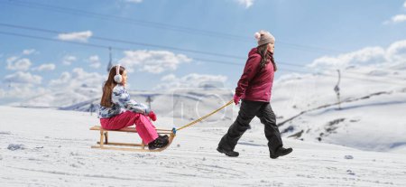 Foto de Imagen de perfil completo de una niña jugando con un trineo de madera en una colina de montaña - Imagen libre de derechos