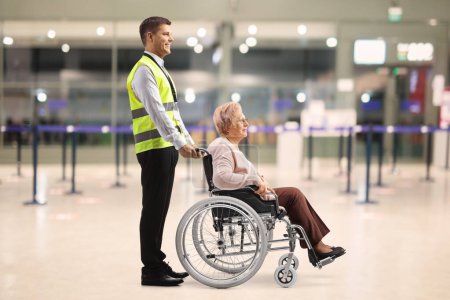 Téléchargez les photos : Assitance worker helping an elderly woman in a wheelchair at the airport - en image libre de droit