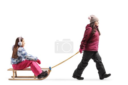 Foto de Girls playing with a wooden sleigh at a snowy mountain on a sunny day - Imagen libre de derechos