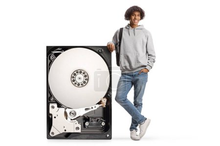 Foto de Estudiante afroamericano masculino apoyado en un gran disco duro aislado sobre fondo blanco - Imagen libre de derechos