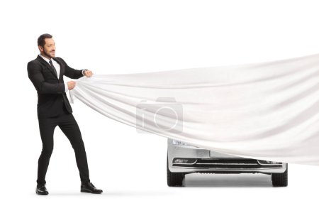Foto de Businessman pulling a white piece of cloth in front of a new car isolated on white background - Imagen libre de derechos