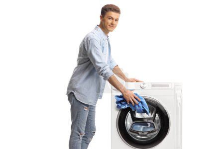 Téléchargez les photos : Jeune homme chargeant une machine à laver isolée sur fond blanc - en image libre de droit