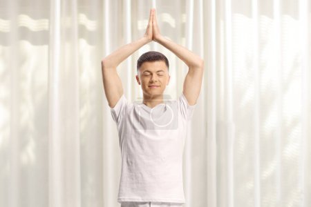 Foto de Joven con ropa blanca de pie y practicando yoga - Imagen libre de derechos