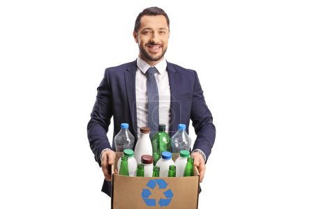 Foto de Joven profesional en traje y corbata sosteniendo una caja con botellas de plástico para reciclar aislado sobre fondo blanco - Imagen libre de derechos