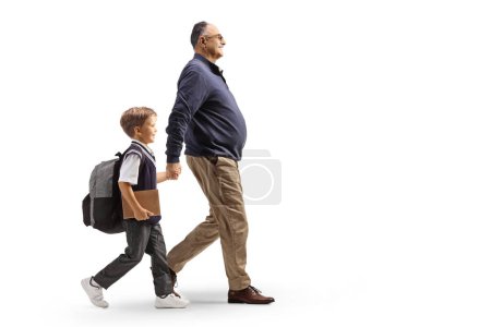 Foto de Foto de perfil completo de un hombre maduro y un colegial caminando y tomados de las manos aislados sobre fondo blanco - Imagen libre de derechos