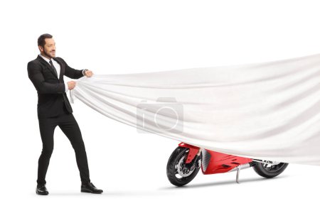 Foto de Man in a suit and tie revealing a red racing motorbike isolated on white background - Imagen libre de derechos