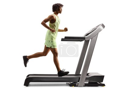 Photo for Full length profile shot of an african american guy running on a treadmill isolated on white background - Royalty Free Image