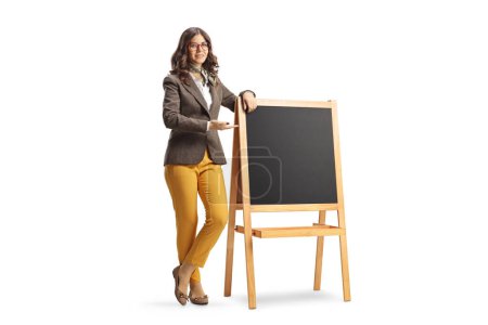 Photo for Full length portrait of a young female teacher pointing at a blackboard isolated on white background - Royalty Free Image