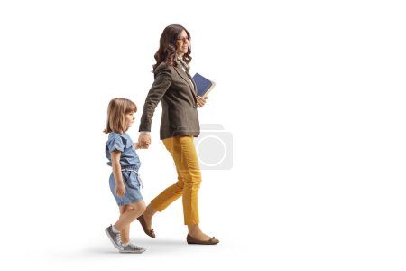 Photo for Full length profile shot of a woman walking carrying books and holding hands with a little girl isolated on white background - Royalty Free Image