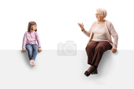 Téléchargez les photos : Enfant assis sur un panneau vierge et écoutant grand-mère parler isolé sur fond blanc - en image libre de droit