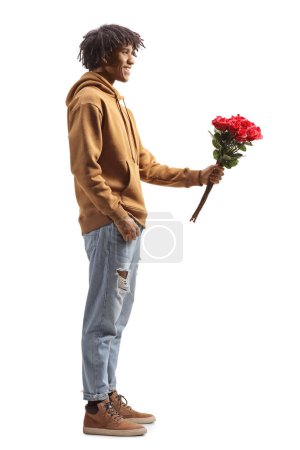 Téléchargez les photos : Full length profile shot of a young african american man giving a bunch of roses isolated on white background - en image libre de droit